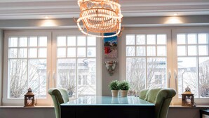 En spiseplads med et bord, stole, en hængende lampe og vinduer med udsigt.
