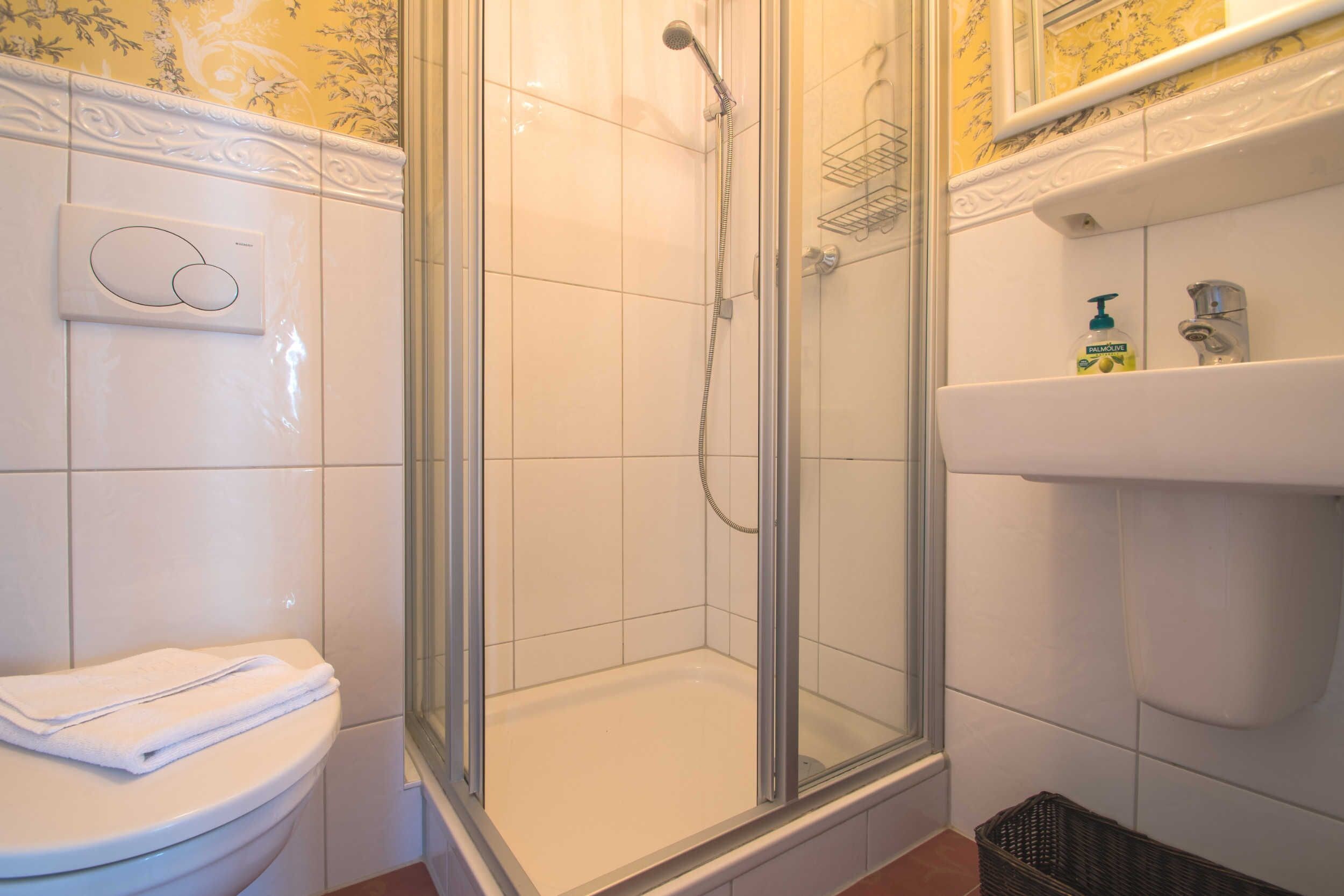 A bathroom with a glass-enclosed shower, a white sink, and a toilet.