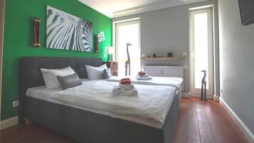 Un dormitorio con dos camas, una pared verde, una obra de arte con estampado de cebra y una estatua de jirafa.
