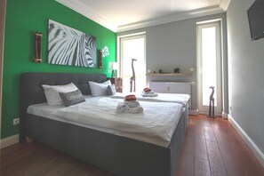 A bedroom with two beds, a green wall, a zebra print artwork, and a giraffe statue. - Villa Hansa, App. 4, 2 bedrooms, 2 bathrooms, in Binz, 2 balconies - App. with 2 bedrooms and 2 bathrooms (Binz)