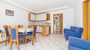 Una cucina compatta con zona pranzo, che include un tavolo con sedie, un'isola piccola e un divano blu.