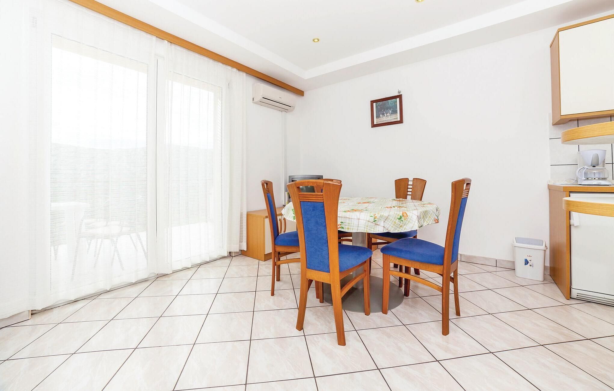 Un coin repas avec une table ronde, six chaises en bois et une nappe à carreaux.