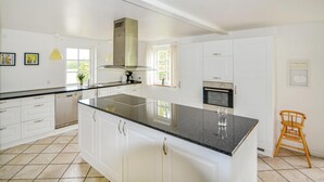 Une cuisine moderne avec des meubles blancs, un plan de travail noir et un four encastré.