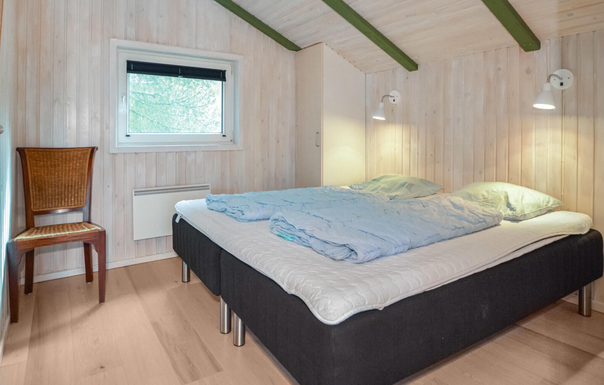 A bedroom with a bed, a chair, a window, and a radiator.