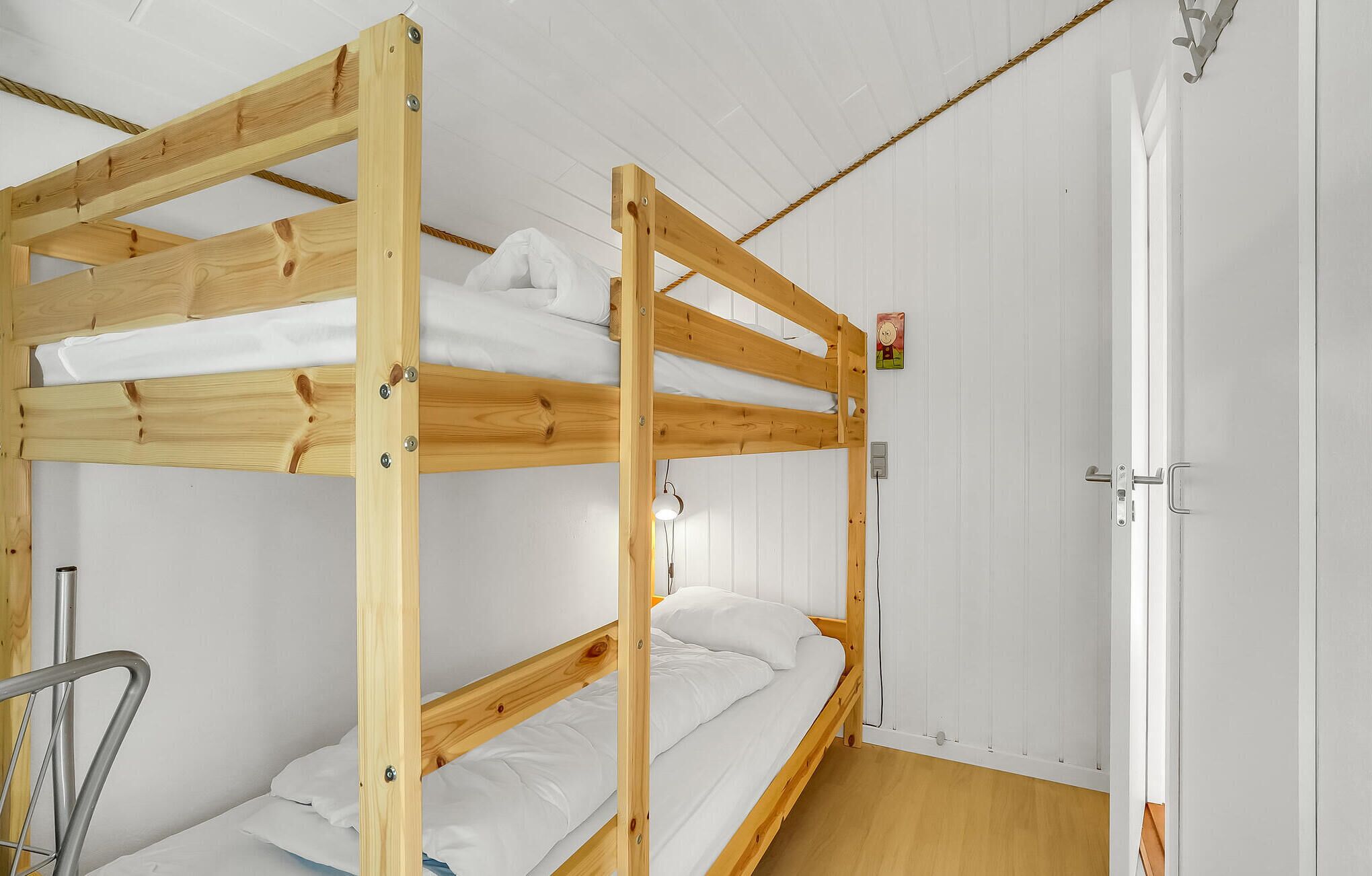 A bunk bed room with white walls and a wooden door.