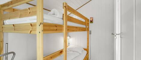 A bunk bed room with white walls and a wooden door.