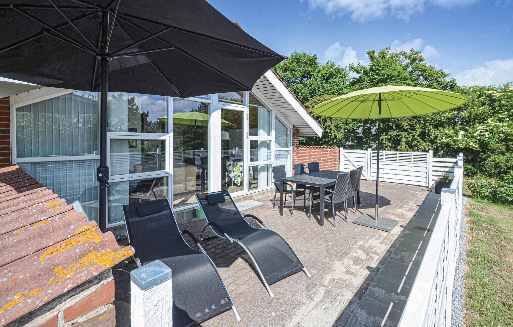 A patio with outdoor furniture, a table, and two umbrellas.