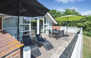 A patio with outdoor furniture, a table, and two umbrellas.