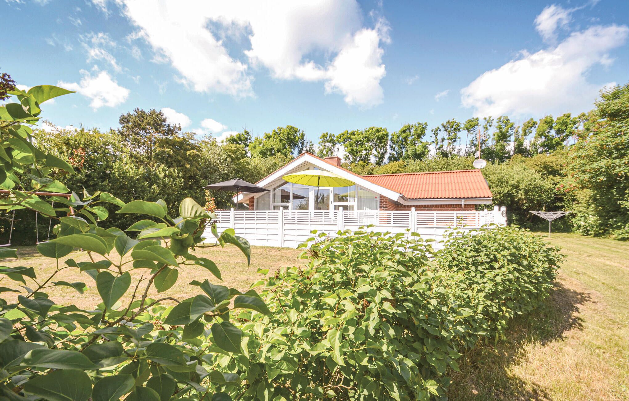 Ein eingeschossiges Haus mit rotem Dach, weißen Außenwänden und einer Veranda.