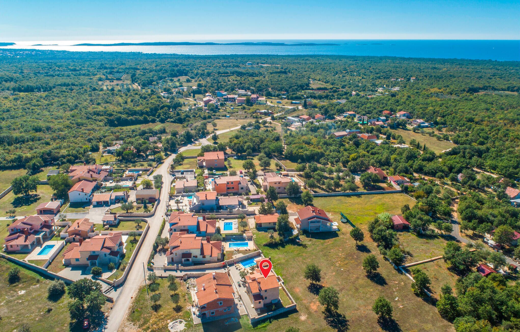 An aerial view of a residential area with houses, a main road, and a large body of water in the background.