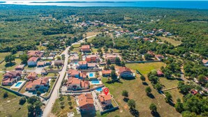 Vista aérea de uma área residencial com casas, uma estrada principal e uma grande massa de água ao fundo.