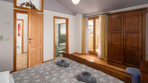 Quarto com cama, guarda-roupa de madeira e banheiro visível por uma porta aberta.