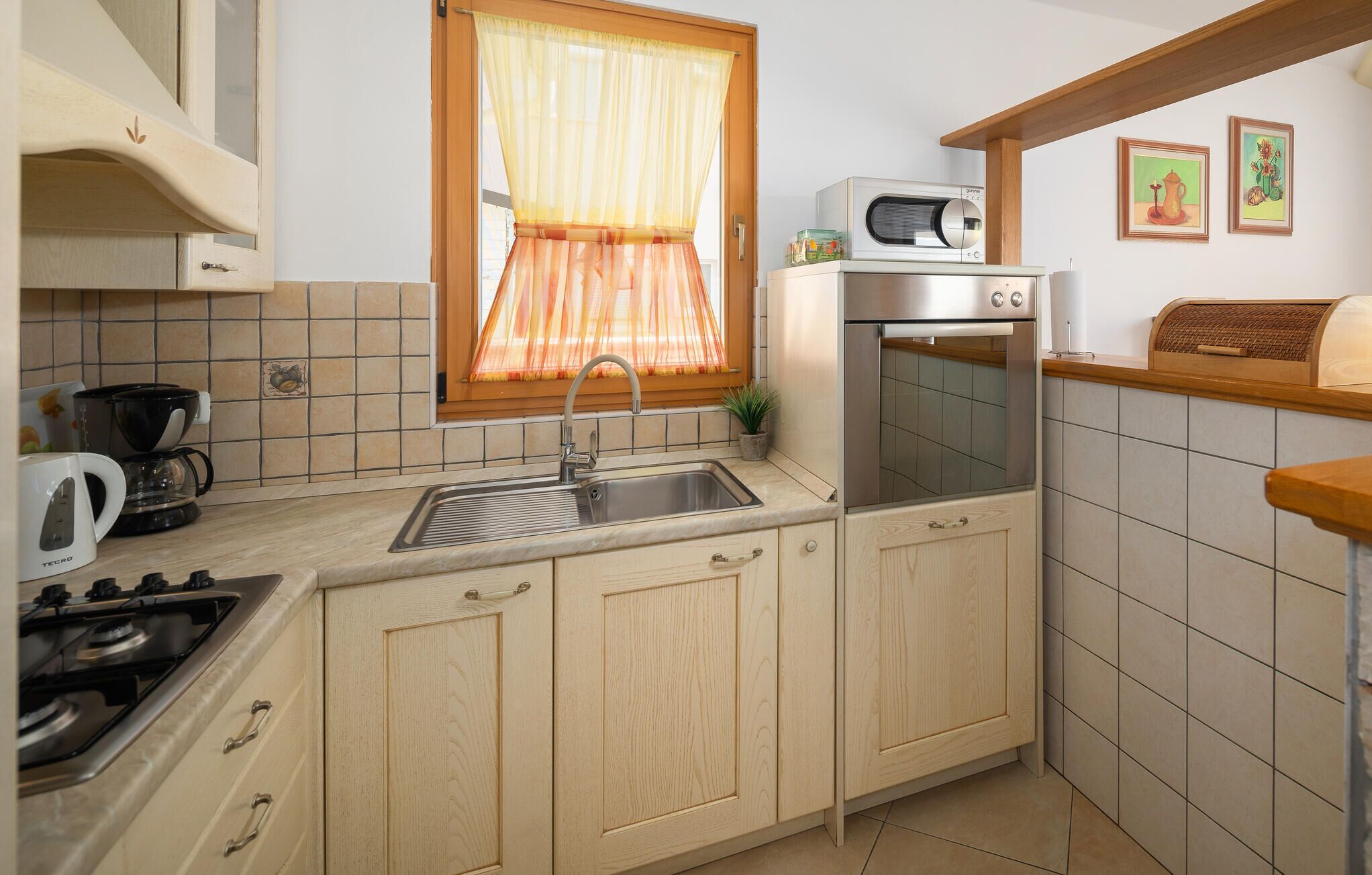 Eine kompakte Küche mit Gasherd, Spüle, Mikrowelle und Backofen.