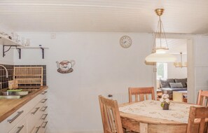 A kitchen with a wooden table and chairs, a clock, and a hanging light fixture. - 2 bedroom cozy home in Ljungby (Ljungby)