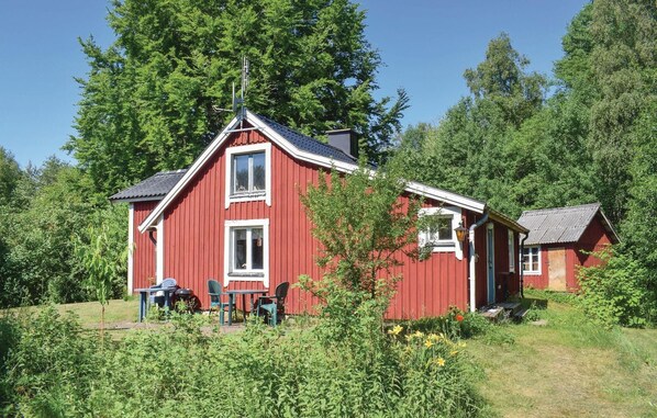 A red wooden cabin with two windows, a small porch, and a table with chairs. - 2 bedroom cozy home in Ljungby (Ljungby)