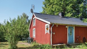 A red wooden house with a blue door, a satellite dish, and a small porch.