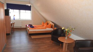 Een slaapkamer met een bed, een stoel, een klein tafeltje, een radiator en een raam met uitzicht.