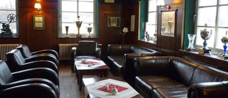 A room with leather sofas, a table with a placemat, and trophies on shelves.