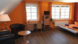 Una habitación con escritorio, silla, cama y una mesita.