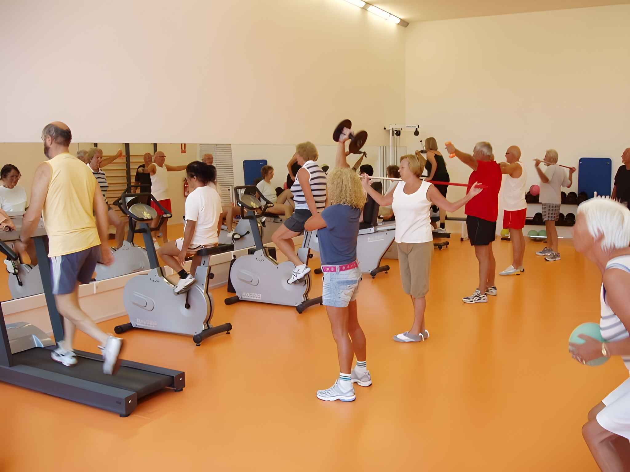 A group of people exercising in a gym with treadmills and stationary bikes.