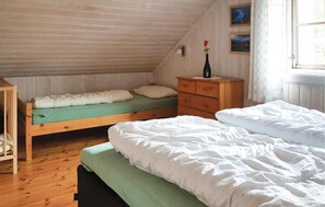 Cozy retreat with two beds, a dresser, and a window offering a view of the outdoors.