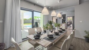 A modern dining area with a long table set for four, featuring black bowls and wine glasses. - Gorgeous home in Barban with sauna (Barban)