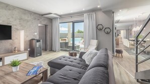 A modern living room with a grey sofa, a wooden coffee table, and a flat-screen TV mounted on the wall. - Gorgeous home in Barban with sauna (Barban)