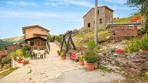 Un rustico edificio in pietra con un cartello di legno che riporta la scritta “AGRITURISMO”.