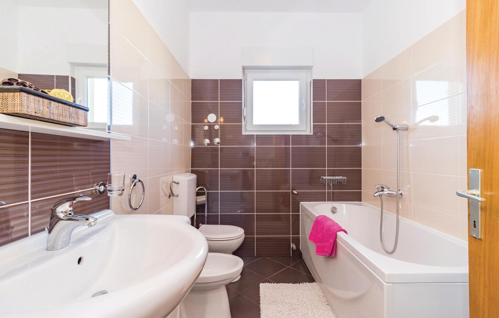 A modern bathroom with a sink, toilet, and bathtub.