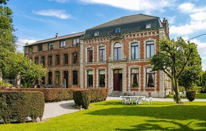 Un grand immeuble à étages, doté d’une façade symétrique, qui combine des matériaux en brique et en pierre, et dont l’entrée principale est marquée par une porte rouge.