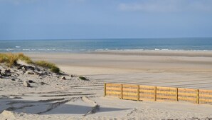 A sandy beach with a wooden fence and footprints leading to the water. - Lovely home in Quiestède with sauna (Quiestède)