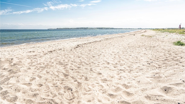 Ein sandiger Strand mit klarem Himmel und ruhiger See.