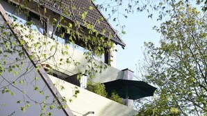 A modern building with a sloped roof, outdoor seating, and lush greenery. - Vacation apartment Kleine Fluchten - Holiday apartment (Sankt Andreasberg)