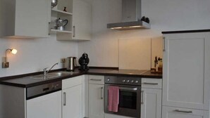 A modern kitchen with white cabinetry, a stainless steel oven, and a black countertop. - Vacation apartment Kleine Fluchten - Holiday apartment (Sankt Andreasberg)