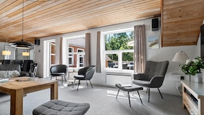 Ein modernes Wohnzimmer mit Holzboden, großen Fenstern und zeitgenössischen Möbeln.
