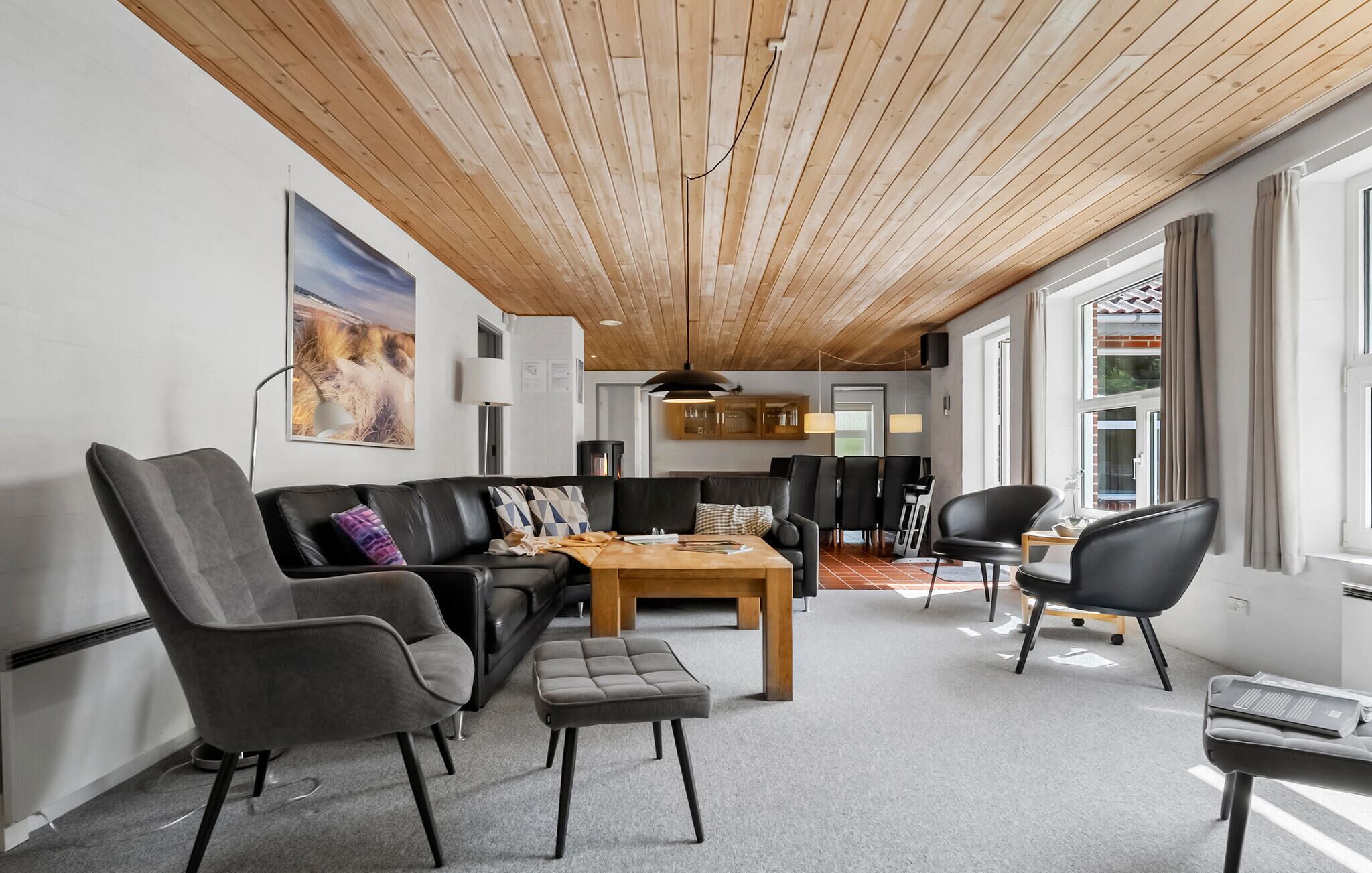 Een moderne woonkamer met houten plafond, een zithoek, een salontafel en uitzicht op het omliggende landschap.