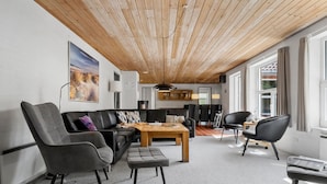 Ein modernes Wohnzimmer mit Holzboden, einer Sofagarnitur, einem Couchtisch und Blick ins Freie.