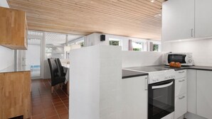 Eine moderne Küche mit weißen Schränken, einer Holzbalkendecke und Blick in einen Essbereich.