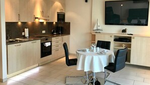 Una cocina moderna con comedor, que incluye un televisor de pantalla plana grande, una decoración con un velero y una pequeña estatua.