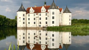 Un edificio grande y blanco con múltiples torres y su reflejo en el agua.