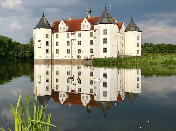 A large, white building with multiple towers and a reflection in the water.