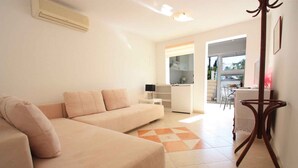 A modern living room with a beige sofa, a small table, and a view to the outside. - Holiday apartment with terrace near the beach (Crikvenica)