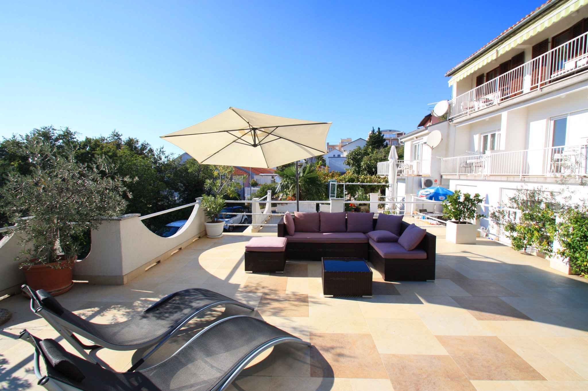 A rooftop patio with a sofa set, a large umbrella, and a chair.