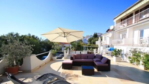 A rooftop patio with a sofa set, a large umbrella, and a chair. - Holiday apartment with terrace near the beach (Crikvenica)
