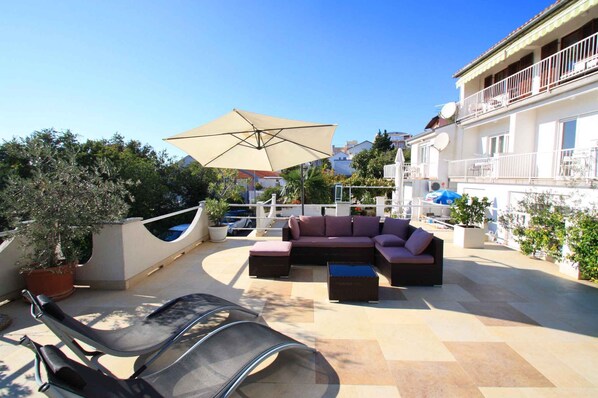 A rooftop patio with a sofa set, a large umbrella, and a chair.