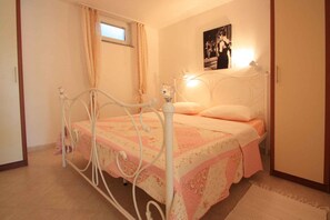 A bedroom with a bed, curtains, a window, a wall-mounted light, and a poster.