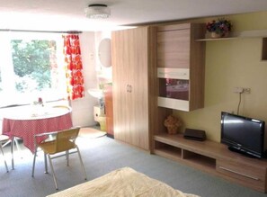 A compact living space with a dining area, a TV, and a wooden cabinet. - Apartment 36 - Apartments on Usedom (Rankwitz)