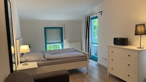 Un dormitorio con cama, mesita de noche, lámpara, cómoda y una ventana con cortinas.