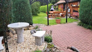Eine Garten-Terrasse mit einem Steintisch und Bänken, umgeben von einer hölzernen Pergola.