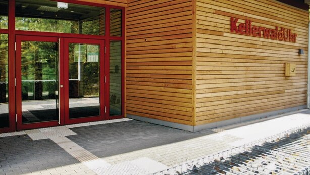 Een gebouw met een houten gevel en een rode deuropening.
